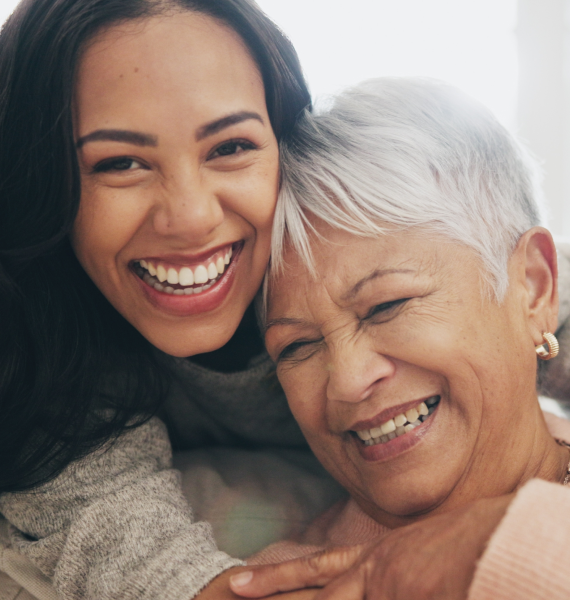 Two women smiling and laughing together outdoors